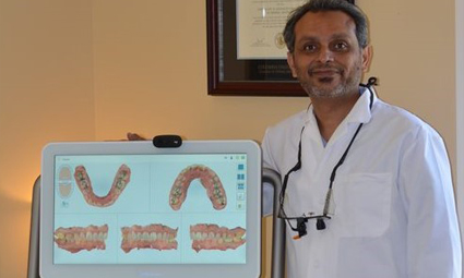 Dentist next to computer screen showing digital models of teeth