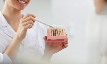 Dentist pointing to model showing dental implant