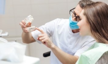 Dentist pointing to model of mouth with dental implants