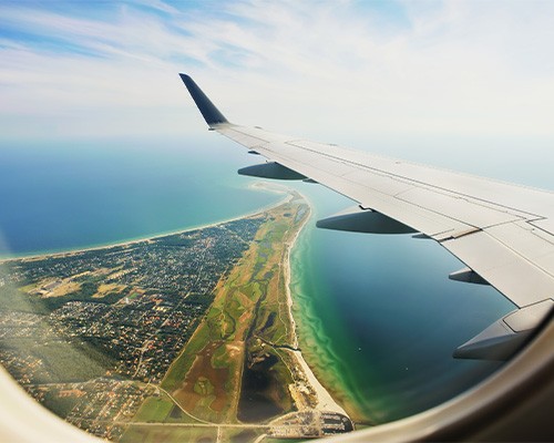 View of airplane wing over city from inside of airplane