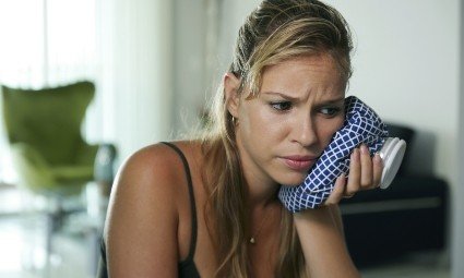 Woman in pain holding ice pack to her cheek