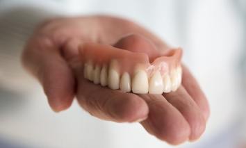 Hand holding a full denture