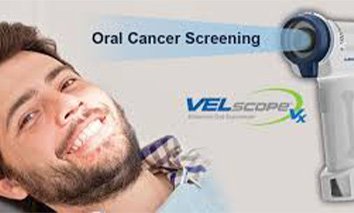 Man smiling next to VELscope oral cancer screening device