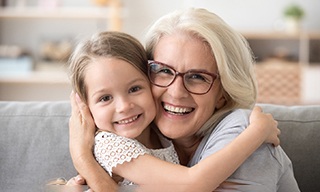 older woman smiling and hugging grandchild