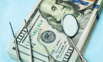 Dental instruments on stack of hundred dollar bills